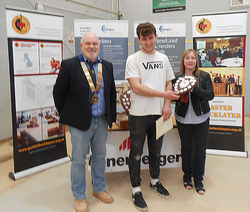 President of the Guild of Bricklayers, Phil Vine Roberts and Veronica Diett, present the junior category award to James Roberts of Northbrook College.