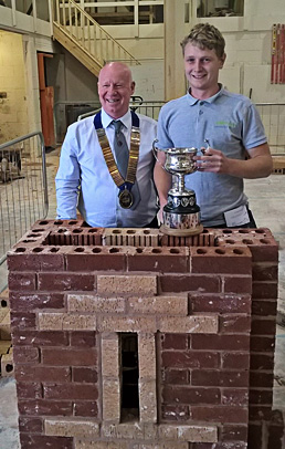 Notts/Lincoln heat senior winner, William Johnson, receives his cup from Guild of Bricklayers president, Kevin Harold
